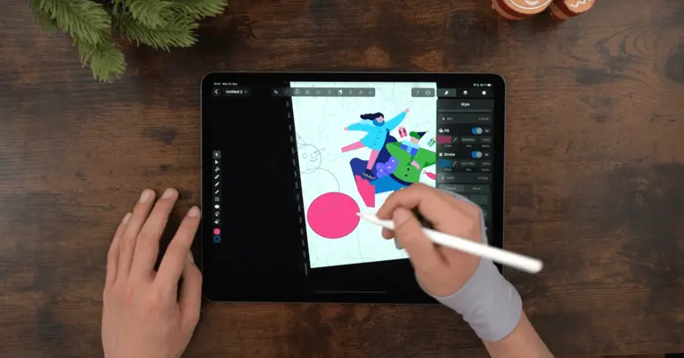 Male hands drawing on an iPad positioned on a wooden table